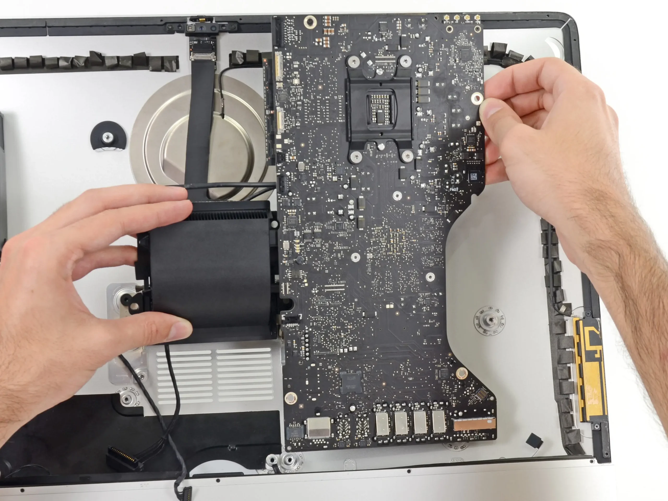 iMac abierto con técnico revisando placa lógica