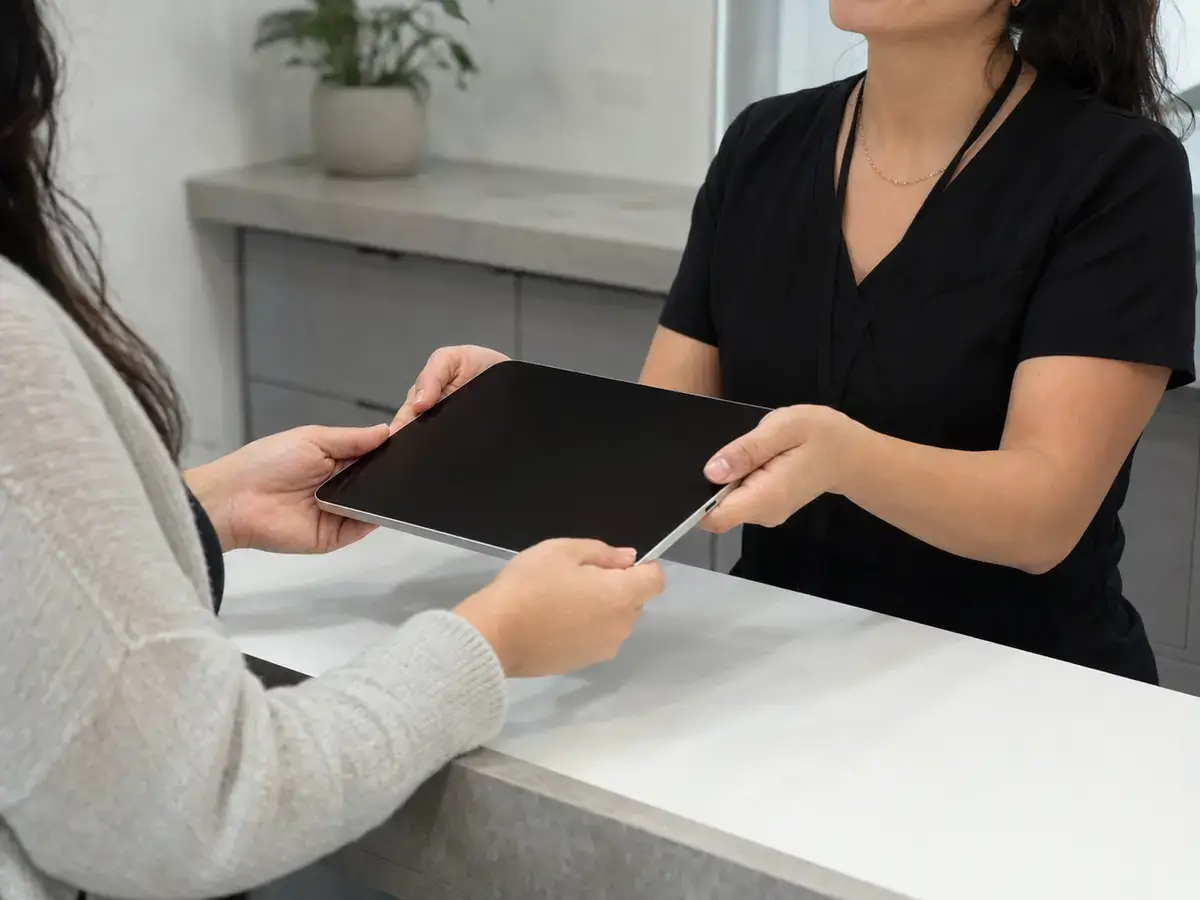 Clienta entregando una tablet a una técnica para su revisión